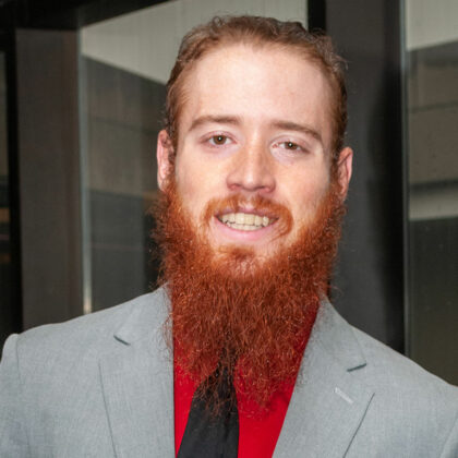 UofL student Daniel Hodges. He is wearing a red button shirt, gray blazer with a black tie.